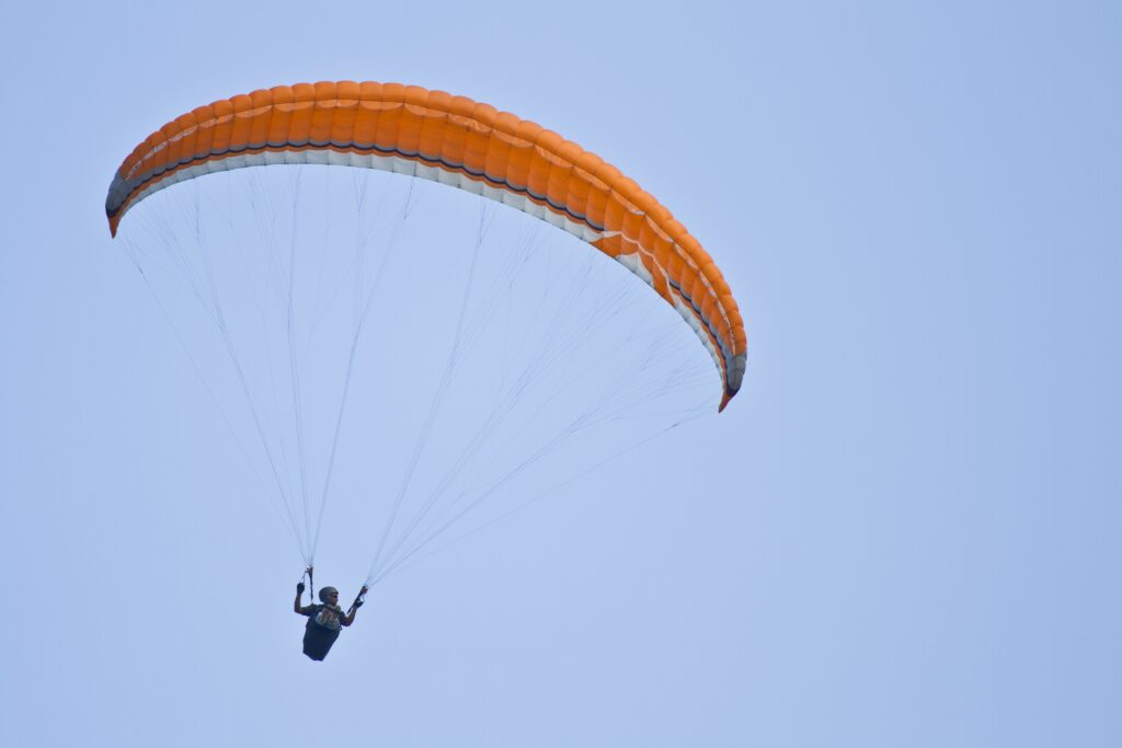amazing shot of a human paragliding on a blue sky background