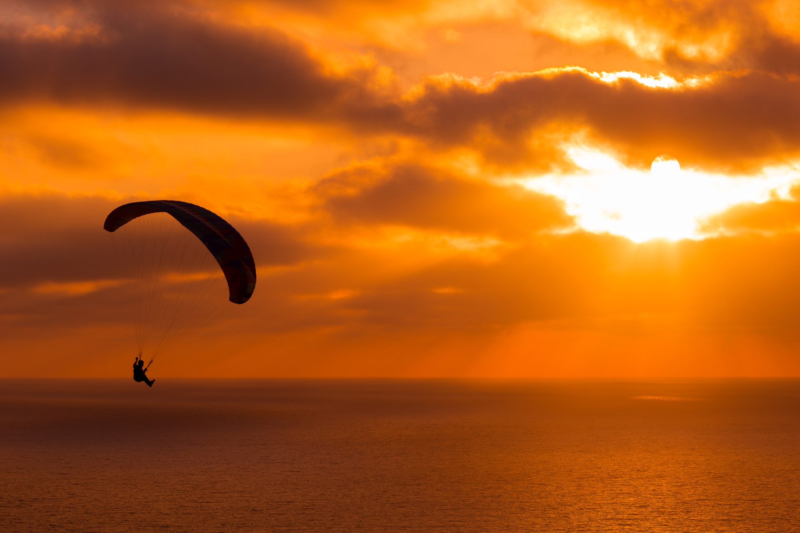 paragliding at sunset with amazing cloudy sky and sun shining through clouds