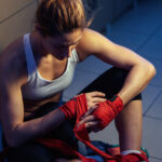 above view of female athlete wrapping hands with boxing straps before sports training.